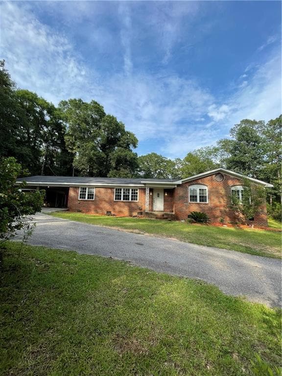 Single story home featuring asphalt driveway, brick siding, and a front lawn