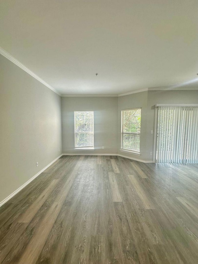Unfurnished living room with crown molding and wood finished floors