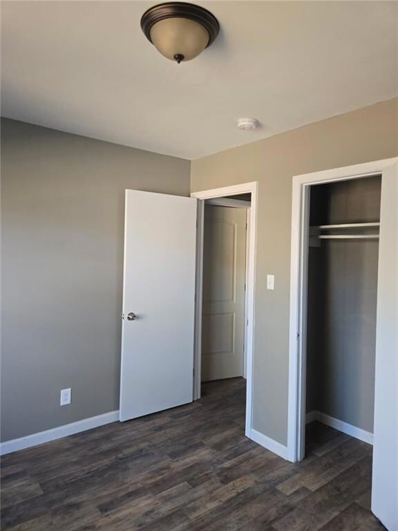 Unfurnished bedroom with dark wood-style floors, a