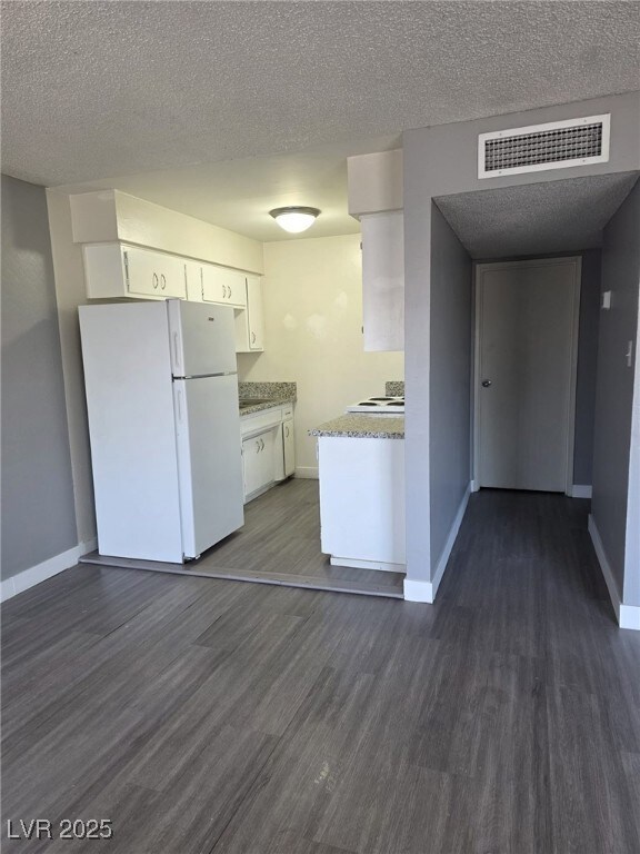 Kitchen featuring freestanding refrigerator, dark