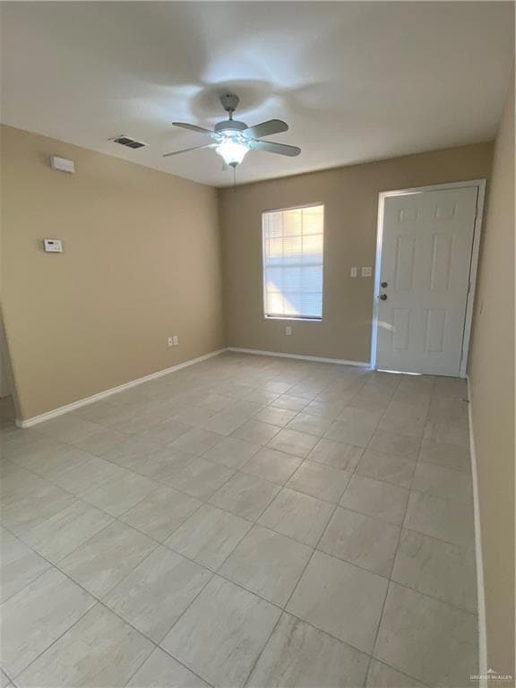 Spare room with baseboards, light tile patterned floors, visible vents, and a ceiling fan