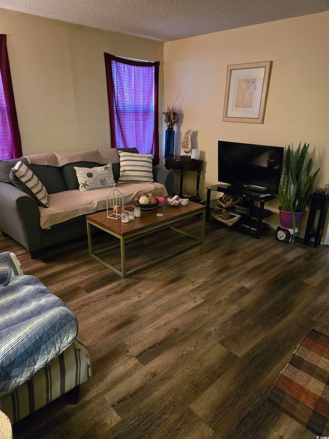 Living area featuring a textured ceiling and wood 