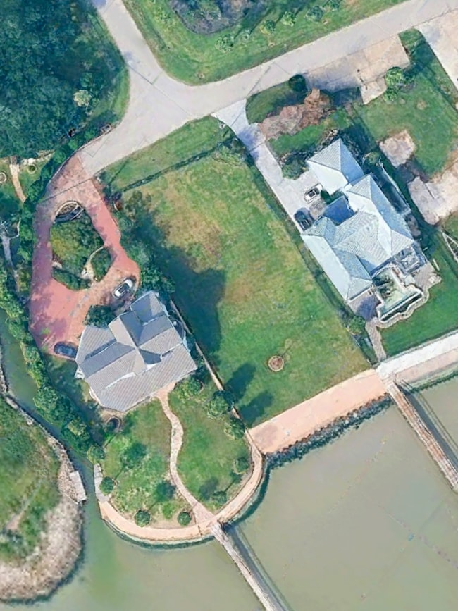 Aerial view showcasing the double lot totaling 18,000+ square feet, located next to 629 Bay Vista Drive in the boutique Bay Vista community. This image highlights the scale of the property, sweeping bay views, and its exceptional placement along the waterfront. A rare opportunity to build a single family home, coastal retreat, or entertainment-focused residence in a peaceful, fenced community with convenient access to Kemah, Galveston, dining, and coastal activities.