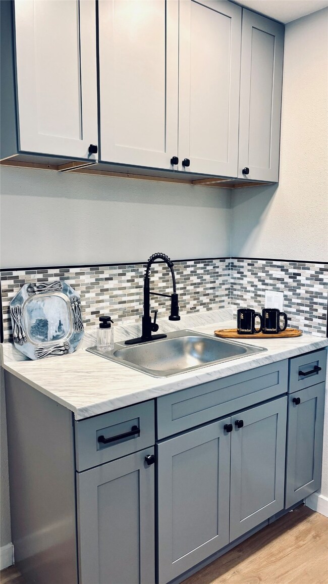 Kitchen featuring light wood-style floors, gray cabinets, and decorative backsplash
