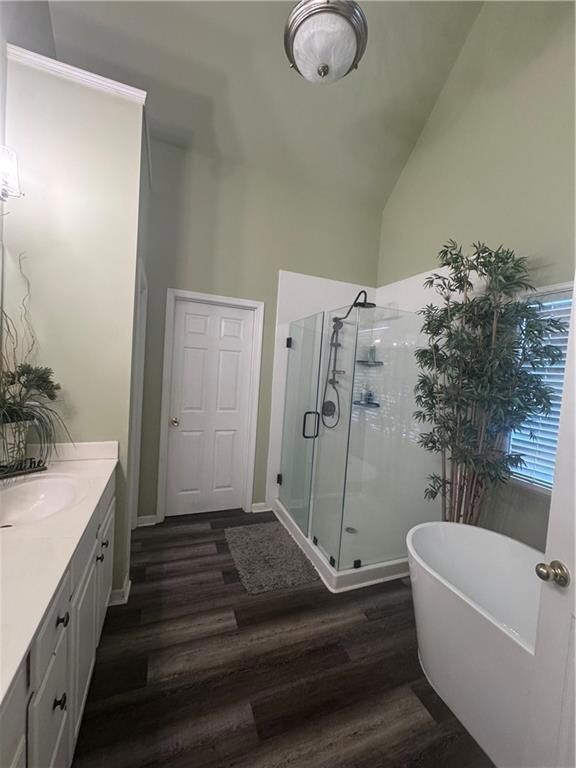 Bathroom with wood finished floors, vanity, a shower stall, and a soaking tub