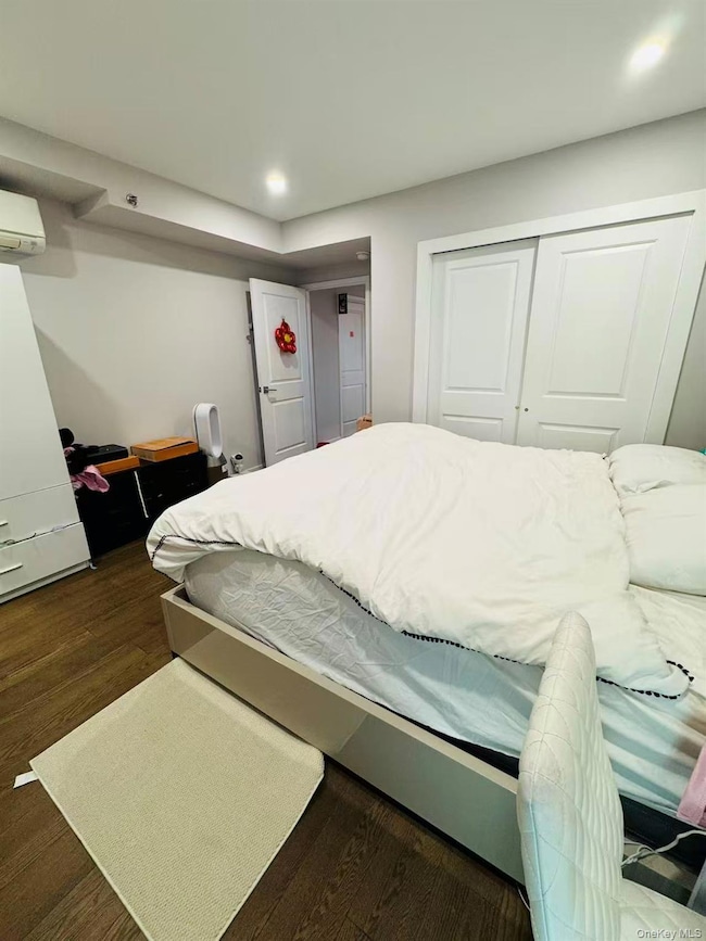 Bedroom with dark wood-type flooring, a wall mounted air conditioner, a closet, and recessed lighting