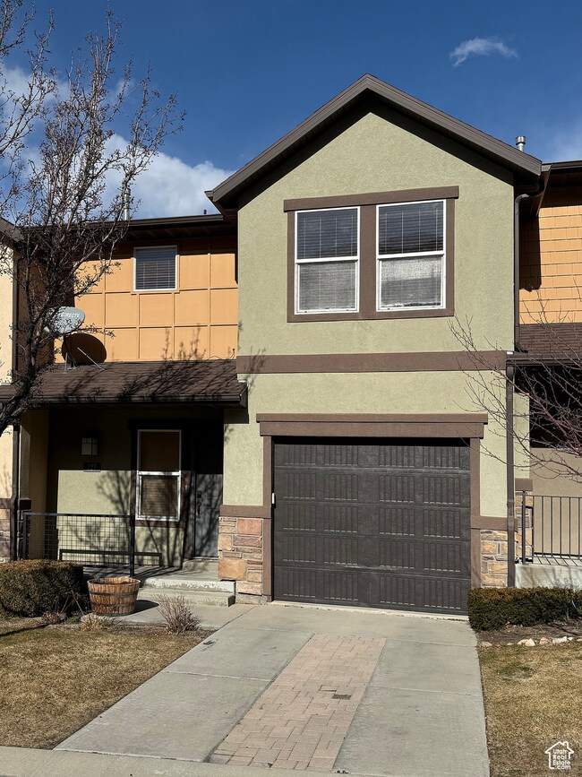 View of front of home featuring stucco siding, covered porch, an attached garage, and concrete driveway