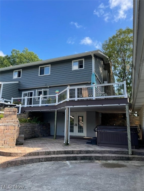 View of front of home with a hot tub and a wooden deck