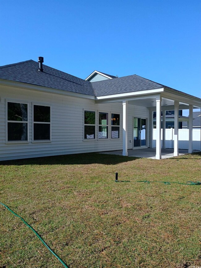 Back of house with a lawn and a patio