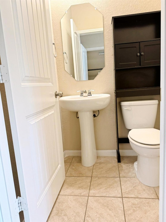 Half bath with tile patterned floors and a textured wall