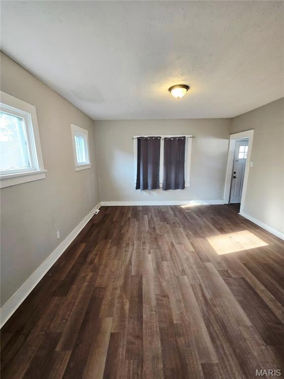 Unfurnished living room with baseboards and dark wood-style flooring
