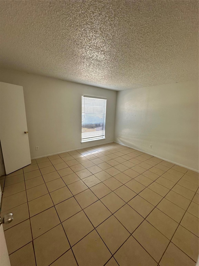 Tiled spare room with a textured ceiling