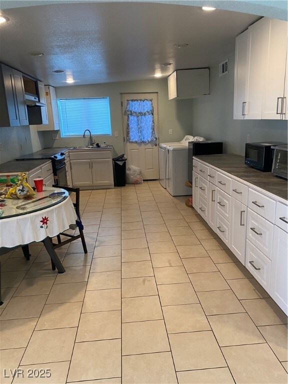 Kitchen featuring washer and dryer, white cabinets