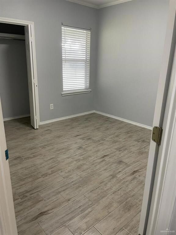 Unfurnished bedroom featuring ornamental molding and light wood-type flooring