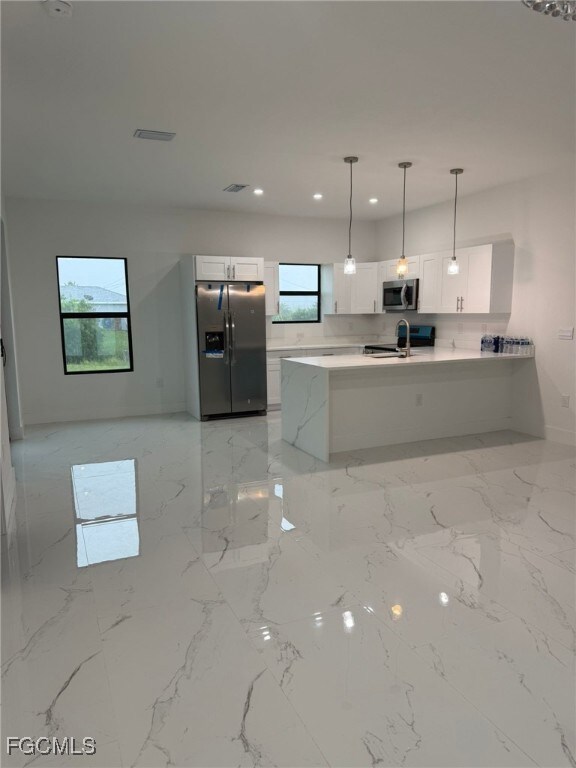 Kitchen featuring a peninsula, white cabinetry, open floor plan, appliances with stainless steel finishes, and recessed lighting