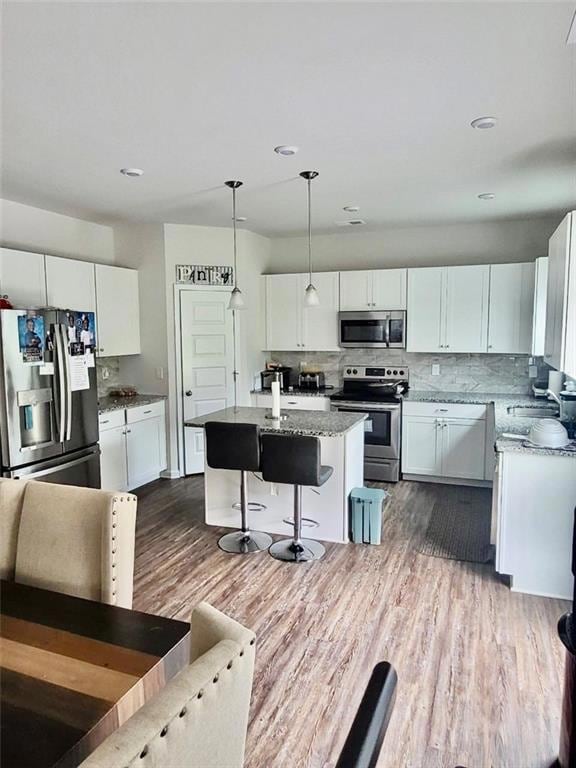 Kitchen with stainless steel appliances, dark wood finished floors, white cabinetry, a center island, and recessed lighting