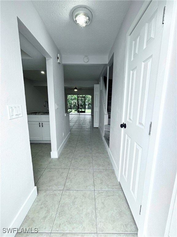 Hallway with a textured ceiling, light tile patter