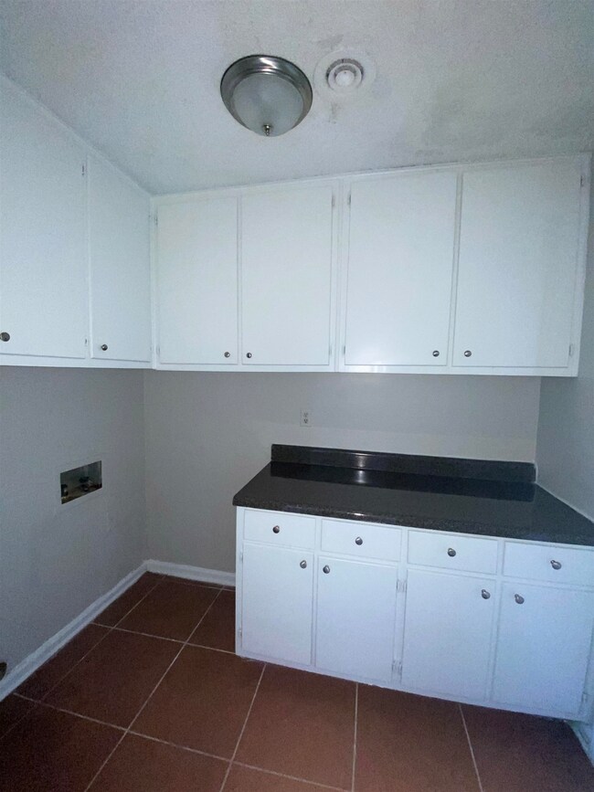 Laundry area with cabinets, dark tile patterned fl