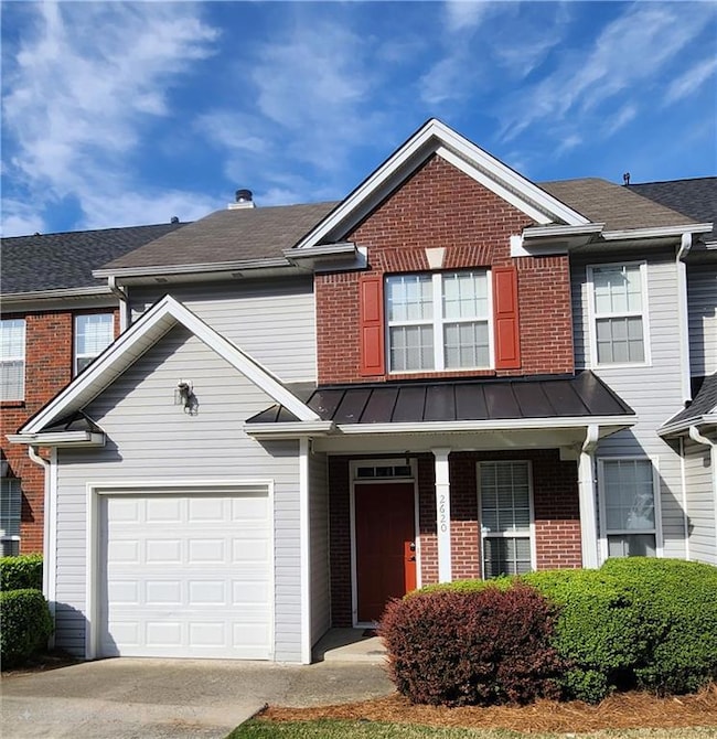 View of front facade with brick siding, driveway, a standing seam roof, and roof with shingles