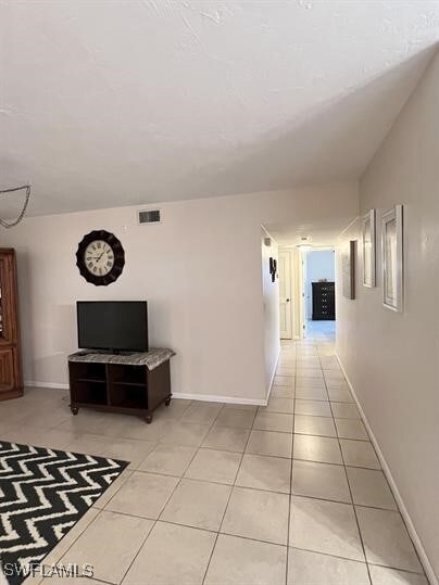 Hallway with baseboards and light tile patterned f