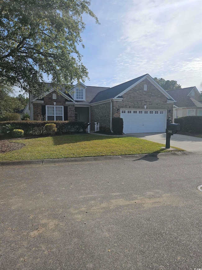 View of front of property featuring concrete driveway, a front yard, and a garage
