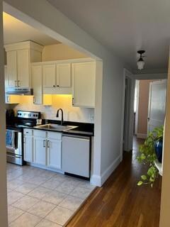 Kitchen with white dishwasher, white cabinetry, stainless steel range with electric cooktop, light wood-type flooring, and sink