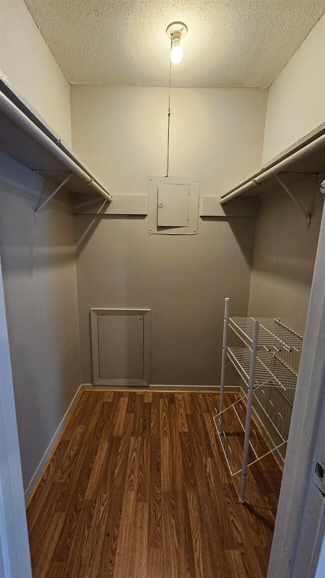 Walk in closet with wood finished floors and electric panel