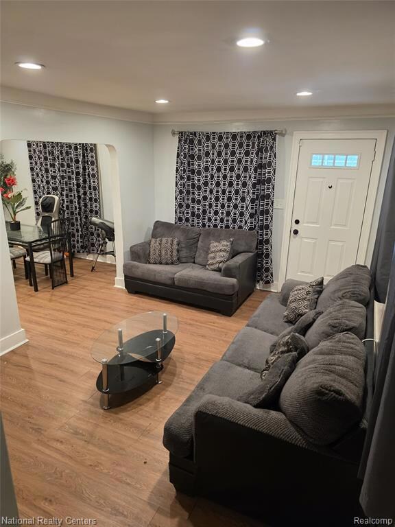 Living area featuring arched walkways, light wood finished floors, and recessed lighting