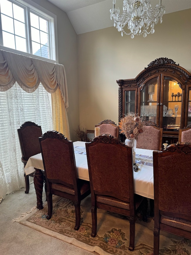 Carpeted dining room featuring a notable chandelie