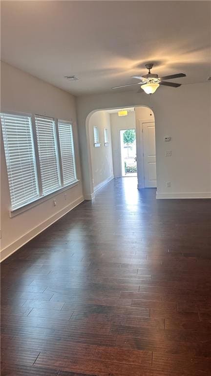 Spare room featuring arched walkways, dark wood-style floors, and ceiling fan