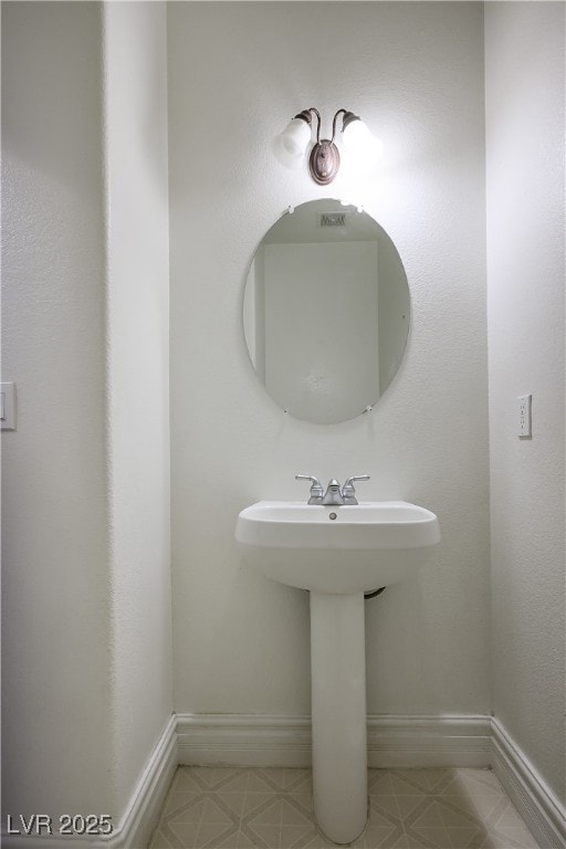 Bathroom with baseboards and a textured wall