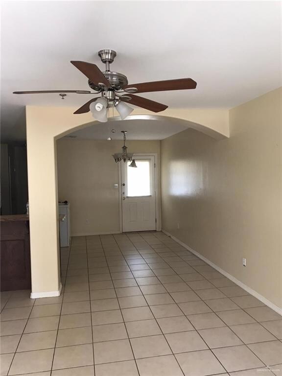 Unfurnished room with light tile patterned floors and ceiling fan with notable chandelier