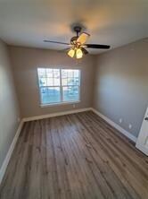 Unfurnished room featuring baseboards, wood finished floors, and a ceiling fan