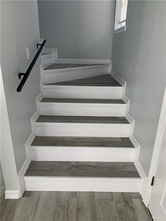 Staircase featuring wood finished floors and a textured wall