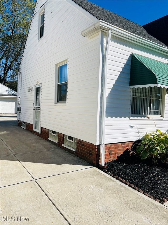 View of home's exterior featuring roof with shingles, a detached garage, and an outbuilding