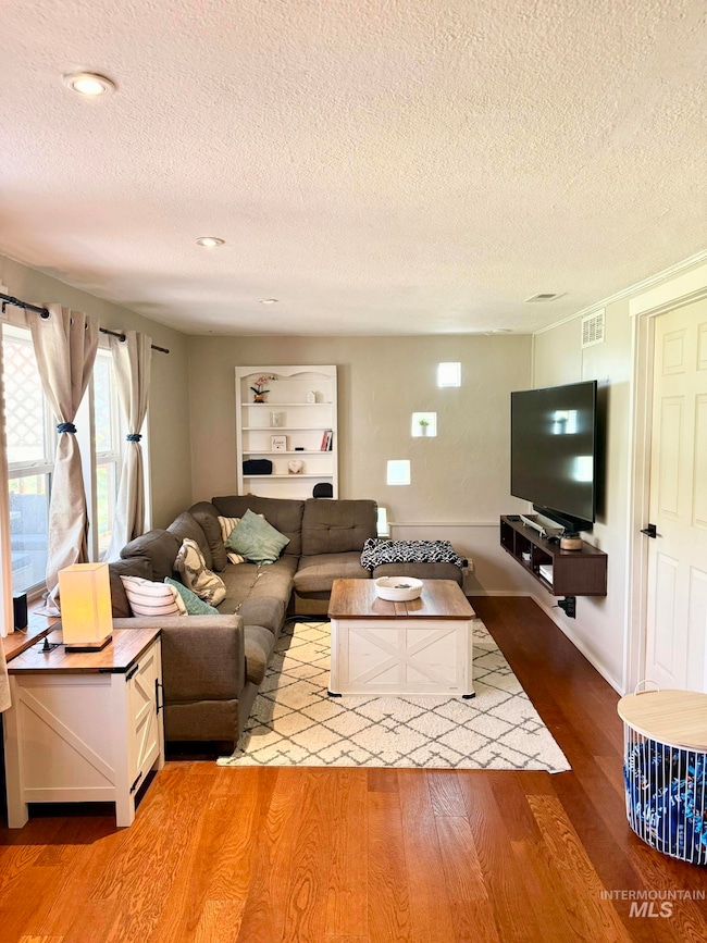 Living room with a textured ceiling and light wood-style flooring
