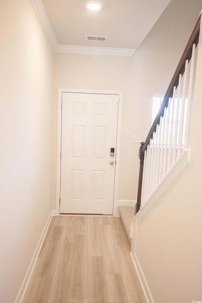 Doorway featuring stairway, light wood-style floors, ornamental molding, and baseboards