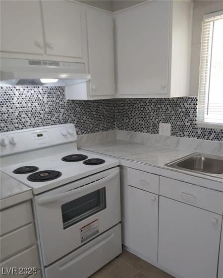 Kitchen with white electric range, white cabinets, light countertops, and under cabinet range hood