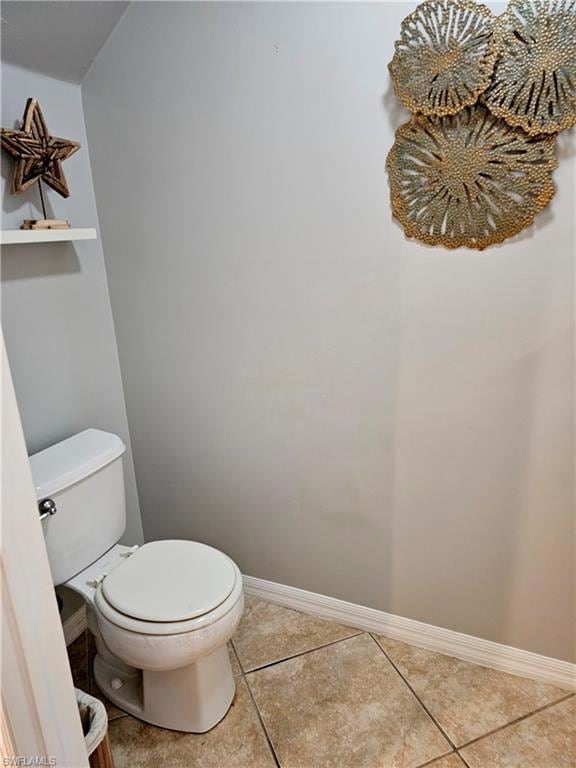 Bathroom with toilet, baseboards, and tile pattern