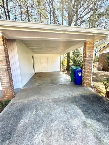 View of parking / parking lot featuring driveway and an attached carport