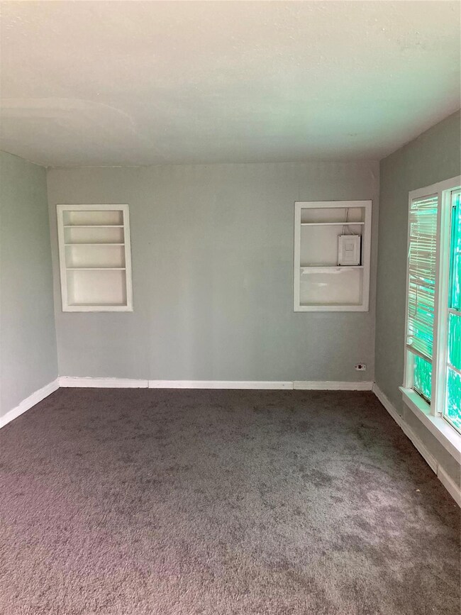 Unfurnished room with built in shelves and carpet 