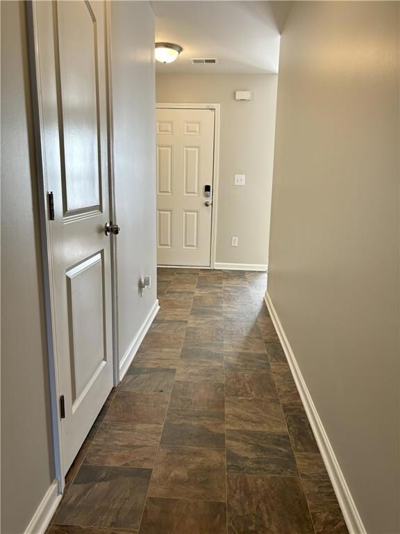Corridor featuring baseboards and stone finish flooring