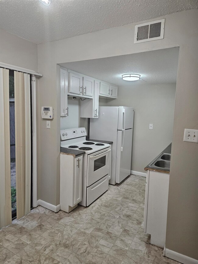Kitchen with white appliances, a sink, a textured 