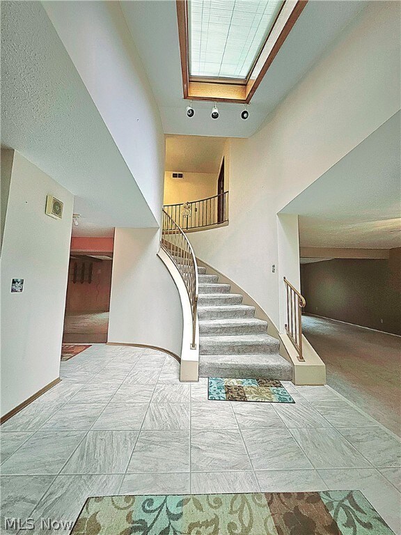 Staircase with a high ceiling and light tile flooring