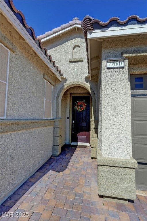 Doorway to property with stucco siding and a tiled
