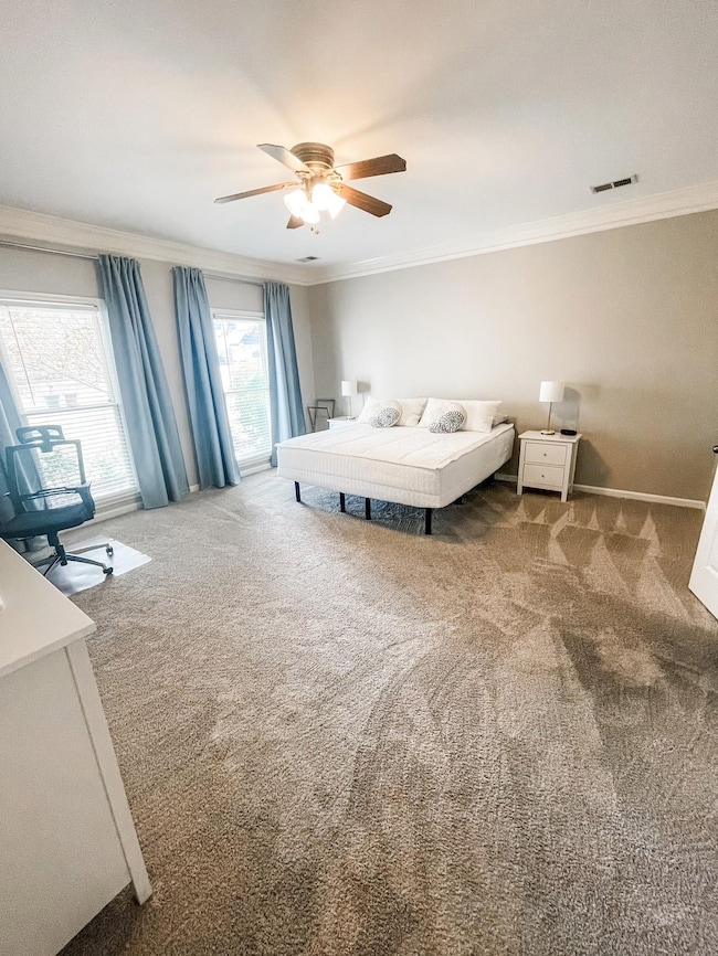 Bedroom with carpet flooring, ceiling fan, and ornamental molding