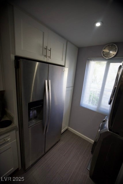Kitchen featuring baseboards, stainless steel fridge, and white cabinets