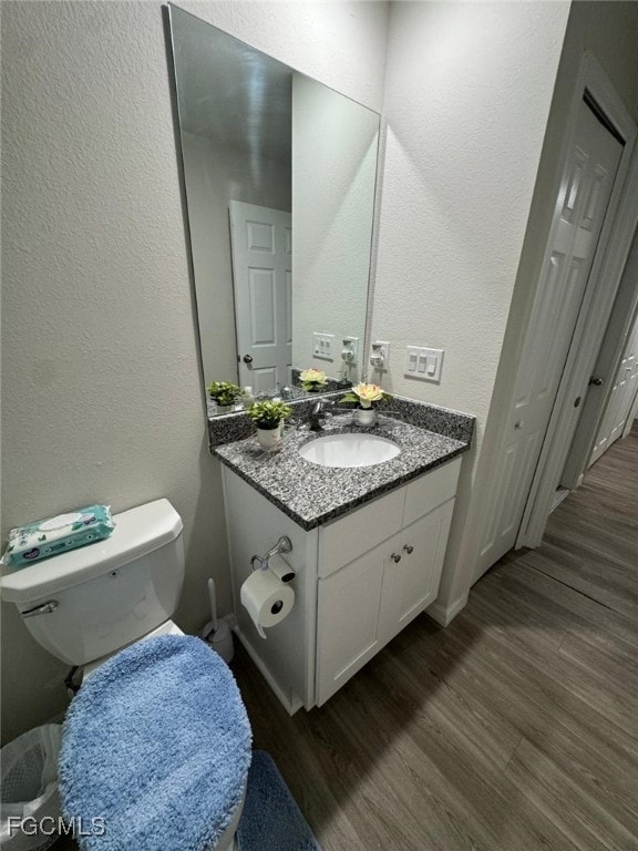 Bathroom with a textured wall, vanity, and wood finished floors