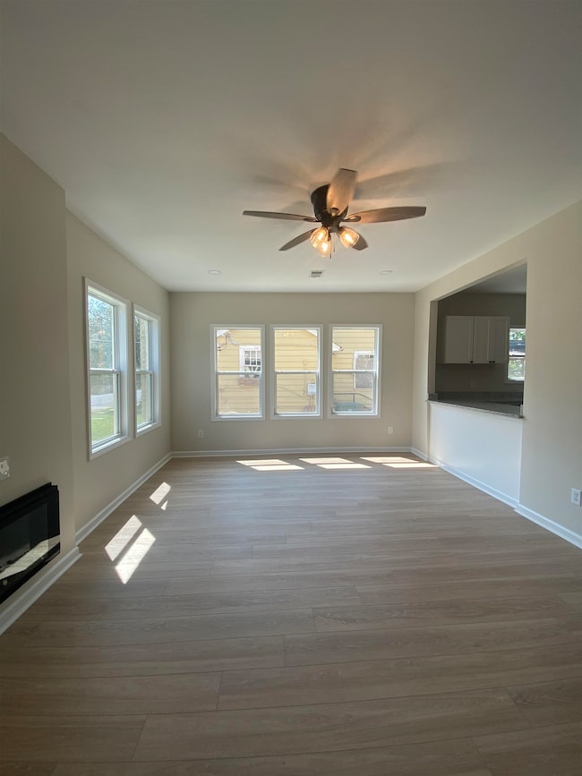 Unfurnished living room with wood finished floors and ceiling fan