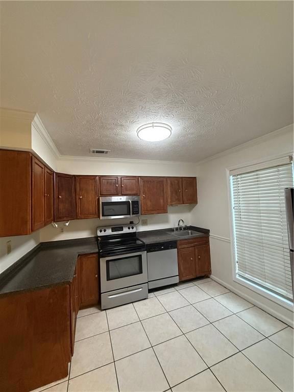 Kitchen featuring dishwasher, range, dark countertops, a textured ceiling, and light tile patterned floors